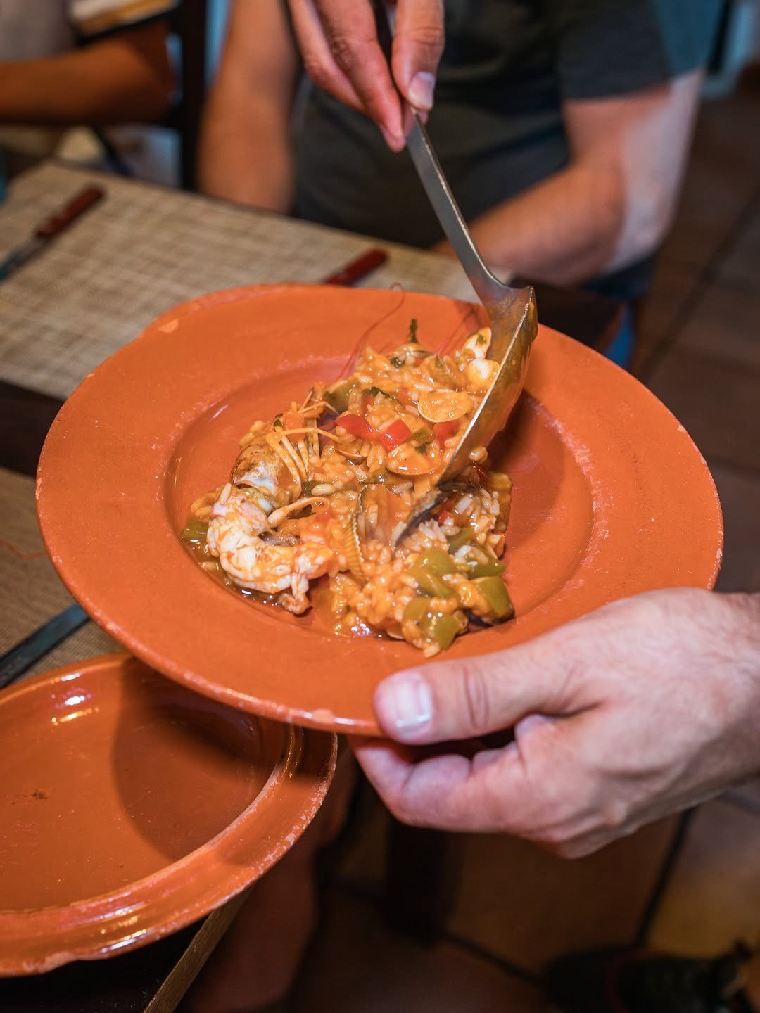 Arroz de marisco servido de um tacho para um prato de barro